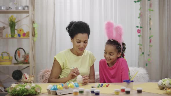 Mom Teaches Her Daughter to Paint Eggs with Paints and Brush