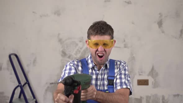 Funny Crazy Man Construction Worker Shoots From an Electric Hammer Perforator