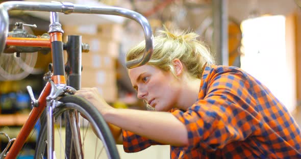 Woman repairing bicycle at workshop 