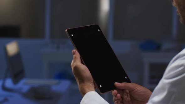 Midsection of caucasian male doctor having video call consultation using tablet computer