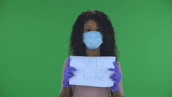 Portrait of Beautiful African American Young Woman in Medical Mask Is Looking at Camera and Holding