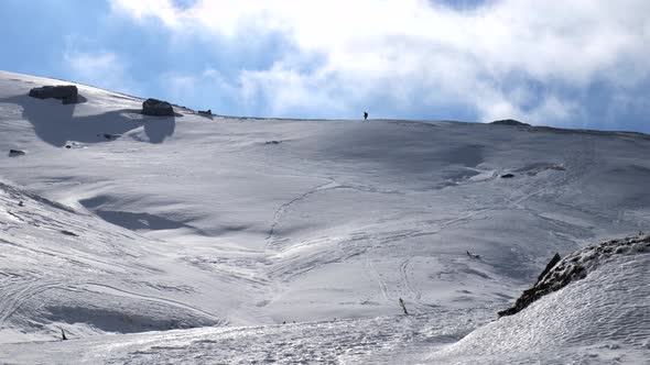 Solo mountaineer walking, hiking on a winter sunny day to reach the mountain peak