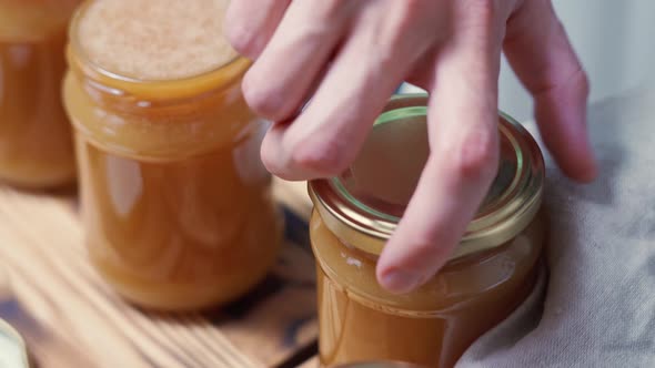 Hands Close Filled Jars with Liquid Homemade Salted Caramel Lids