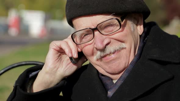 Senior man uses a smartphone while relaxing in a city park