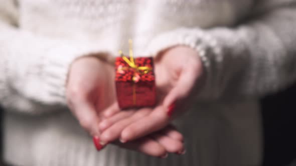 Close-up of the Hands of a Woman Holding a Box with a Gift.