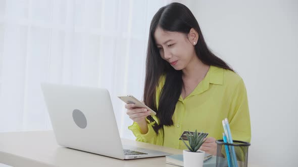 Young asian business woman using smart phone and holding credit card while online shopping.