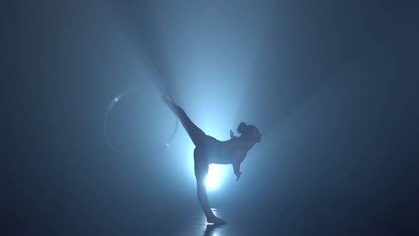 Gymnast Tricks with Hoops on Her Hands and Lifts Her Leg in the Air