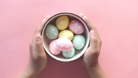 Child Hand Holding a Bowl of Easter Eggs on Pink