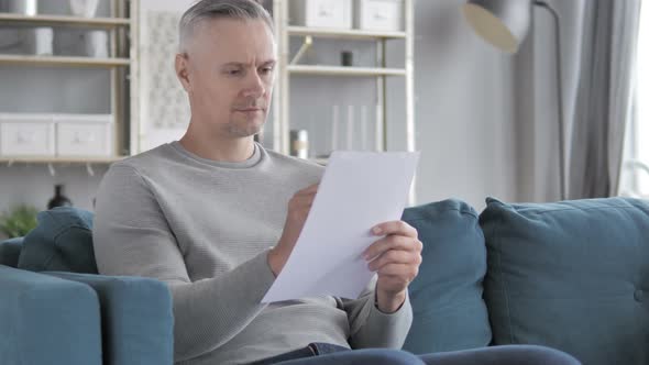 Gray Hair Man Working on Documents While Sitting on Sofa