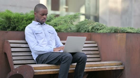 Sick Young African Man Using Laptop Coughing Outdoor 