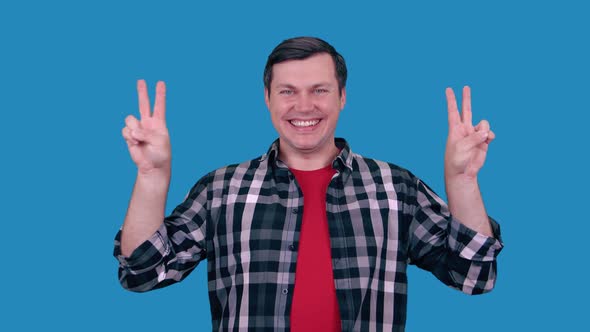 Smiling Cheerful Caucasian Young Man Showing Two Thumbs Up Sign of Victory