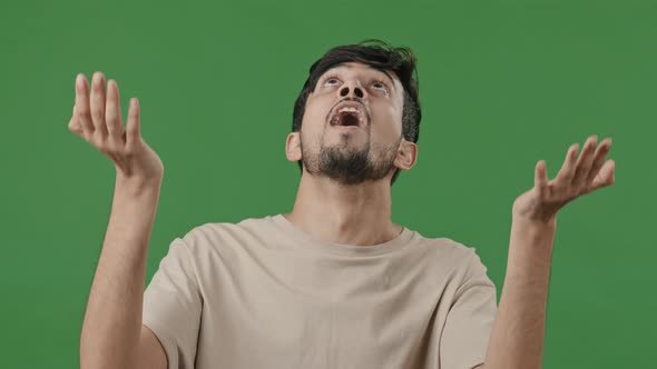 Portrait Excited Young Hopeful Arab Man Says Prayer Standing Studio Green Background Hispanic