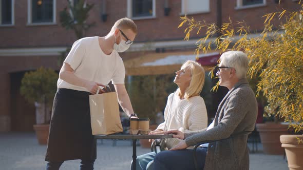 Senior Couple Sitting on Restaurant Terrace Waiting for Takeaway Order