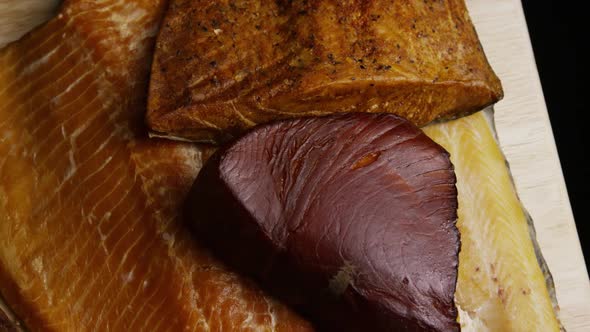 Rotating shot of a variety of delicious, premium smoked meats on a wooden cutting board 