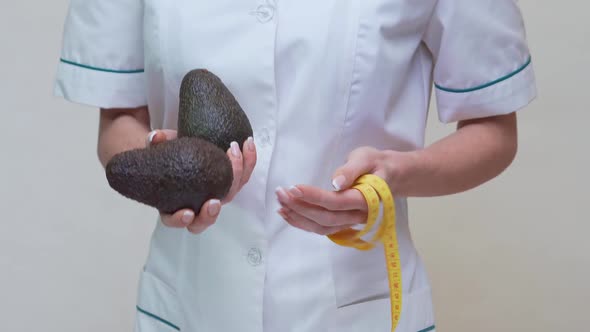 Nutritionist Doctor Healthy Lifestyle Concept - Holding Organic Avocado Fruit and Measuring Tape