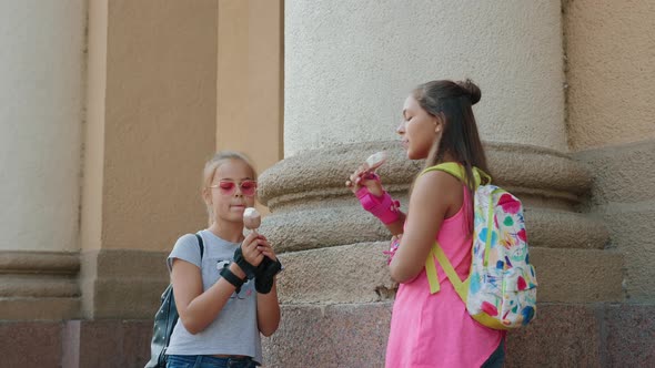 Two Female Friends Eating Ice Cream and Chatting in City