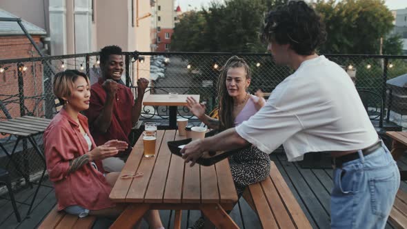 Friends Eating Snacks and Drinking Beer at Rooftop Bar