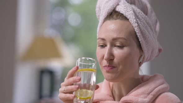 Slim Young Woman Drinking Lemon Detox Water in Slow Motion Enjoying Taste and Looking at Camera