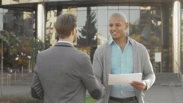 Handsome Young Businessman Shaking Hands with His Colleague Outdoors