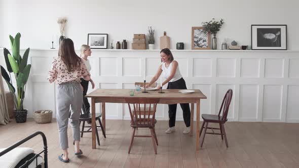 A young woman sets the table for dinner. Woman setting table in stylish kitchen