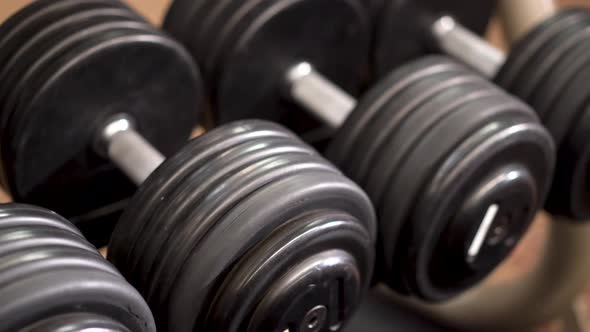 Closeup slow slider shot to the left looking down on row of dumbbells on a rack.