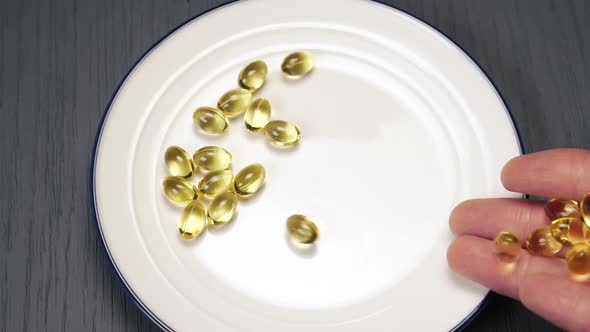 Falling Omega 3 Pills from hands into a white plate with a blue border 