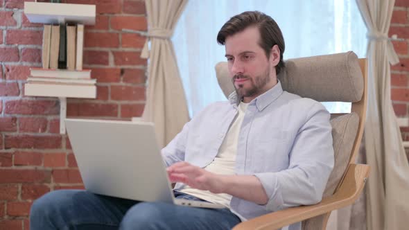 Casual Young Man Working on Laptop on Sofa