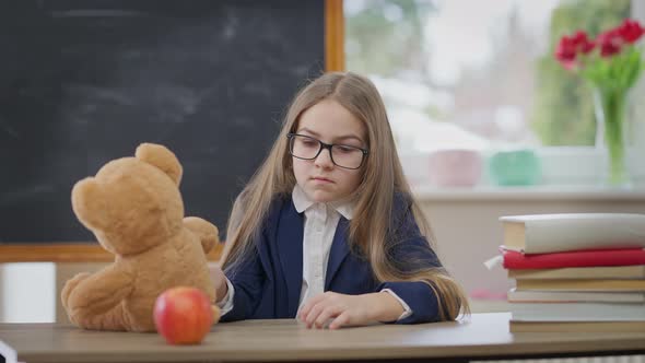 Rack Focus From Teddy Bear to Schoolgirl Gesturing Thumb Up Smiling Looking at Camera