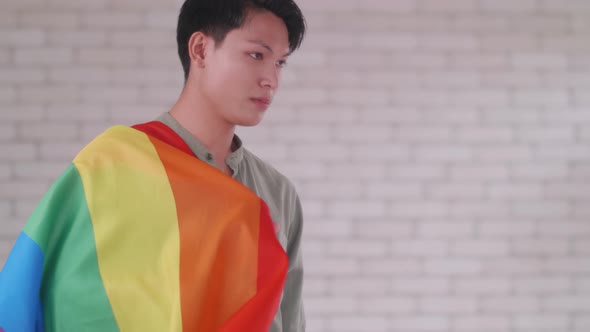 Portrait of Asian gay man holding a rainbow flag.