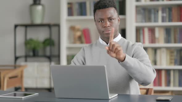 African Man Shaking Head As No Sign While Using Laptop in Library