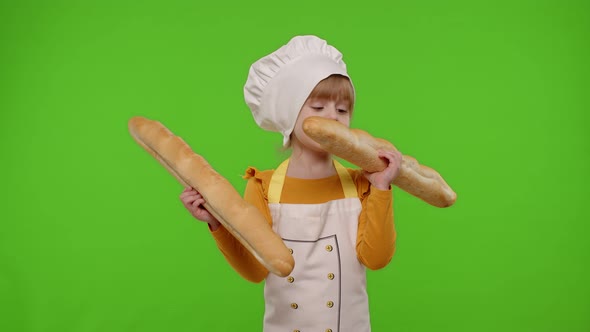 Child Girl Cook Chef Baker in Apron and Hat Sniffing Two Baguettes Fooling Around Making Faces