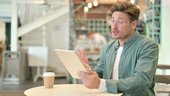 Professional Middle Aged Man Doing Video Chat on Tablet in Cafe 