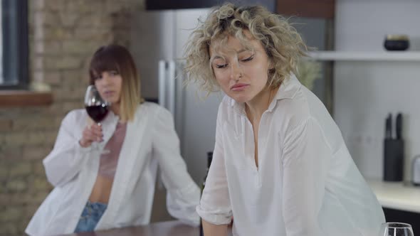 Upset Beautiful Woman Looking Away Thinking As Blurred LGBT Partner Drinking Red Wine at Background