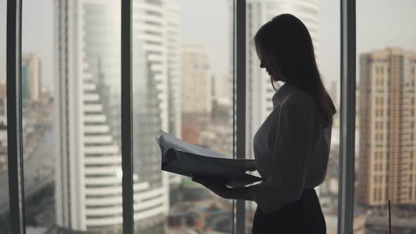 Portrait of a Business Woman with a Folder for Documents in His Hands. Girl Silhouette on a