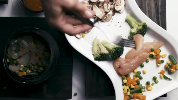 woman using a fork to put chicken in a pot