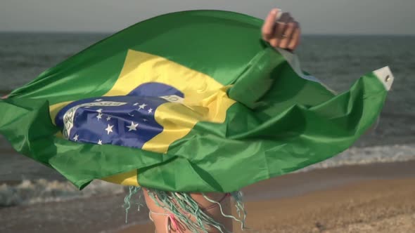 Attractive Woman in a Swimsuit on the Sea Beach with the Flag of Brazil Closeup