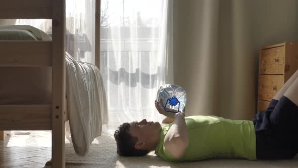 Young Sportsman in Green Tshirt Lifts Large Water Bottle