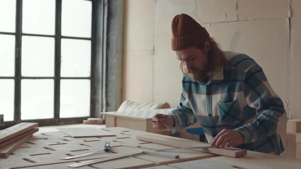 Joiner Making Blueprint on Plank in Carpentry Workshop