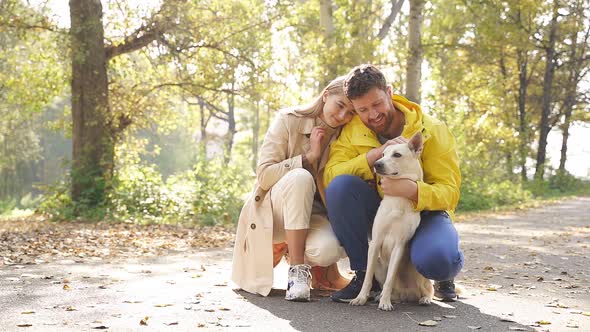 Portrait of a Smiling Young Couple Loving Their Dog, Walking Their Dog on a Sunny Autumn Day