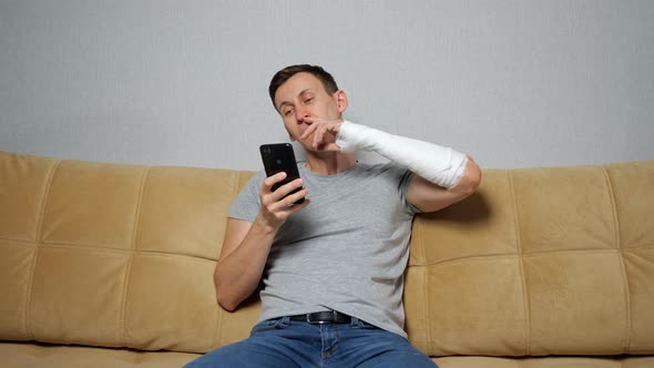 Brunet Man Picks Nose with Broken Arm Scrolling Social Media