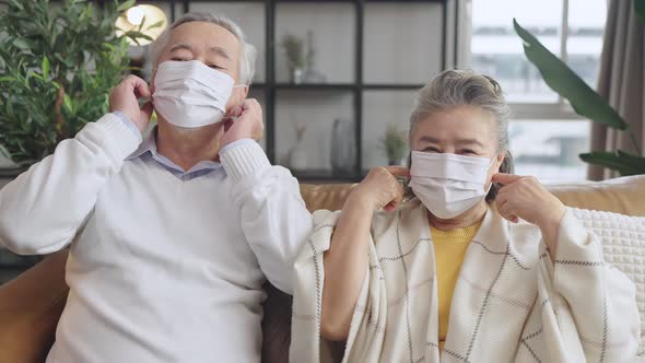 old senior asian retired couple sit relax together and taking off face mask protection