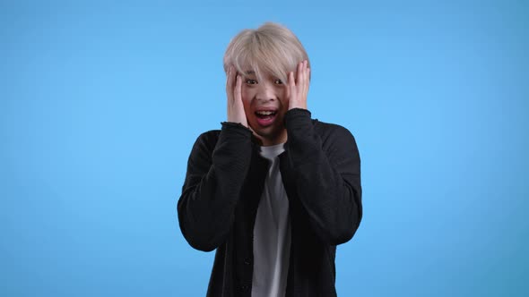 Frightened and Screaming Asian Man Shocked Isolated Over Blue Background