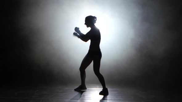 Champion Boxer Sends the Punches. Silhouette. Light From Behind. Black Background. Side View
