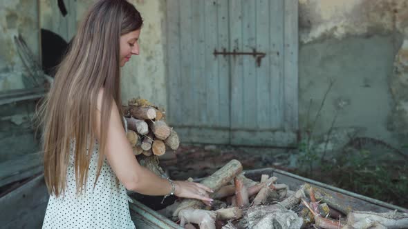 Longhaired Woman Takes Wood Out of Cart to Fire Up Stove