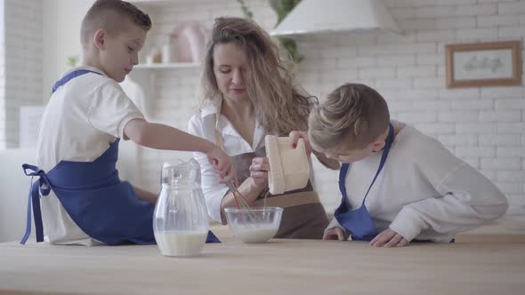 Pretty Woman and Her Two Sons Cooking Making Dough in the Kitchen, the Boys Helping Mother