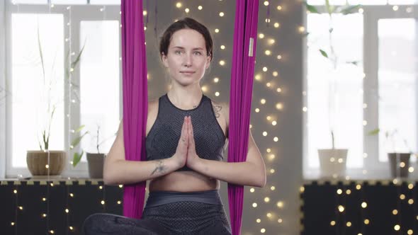 Young Woman Swinging in the Yoga Hammock with Her Palms Put Together