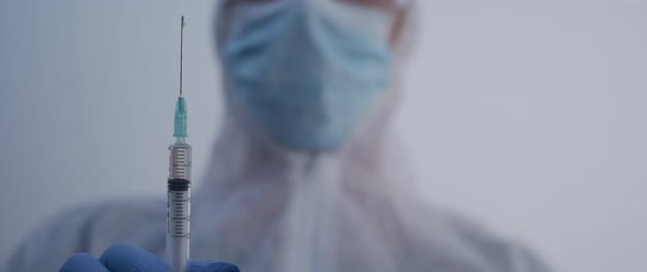 person holding a syringe full of fluid with a dripping needle slow motion