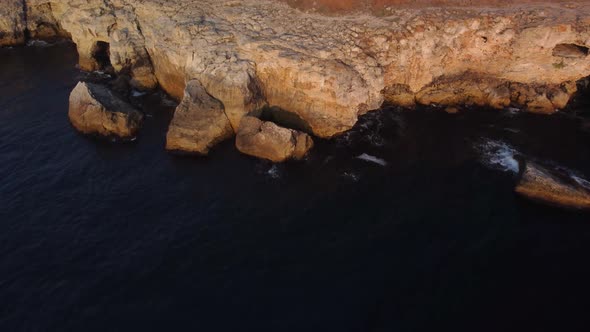 Drone top down aerial view of waves splash against rocky seashore, background. Flight over high clif