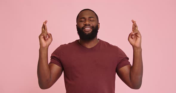 Young African American Man Crossing Fingers Isolated on Pink Background
