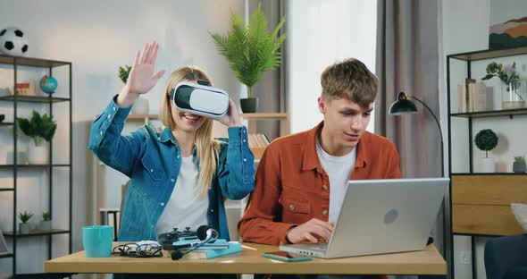 Blond Girl Wearing Virtual Reality Headset Watching Futuristic Vision when Handsome Positive Guy